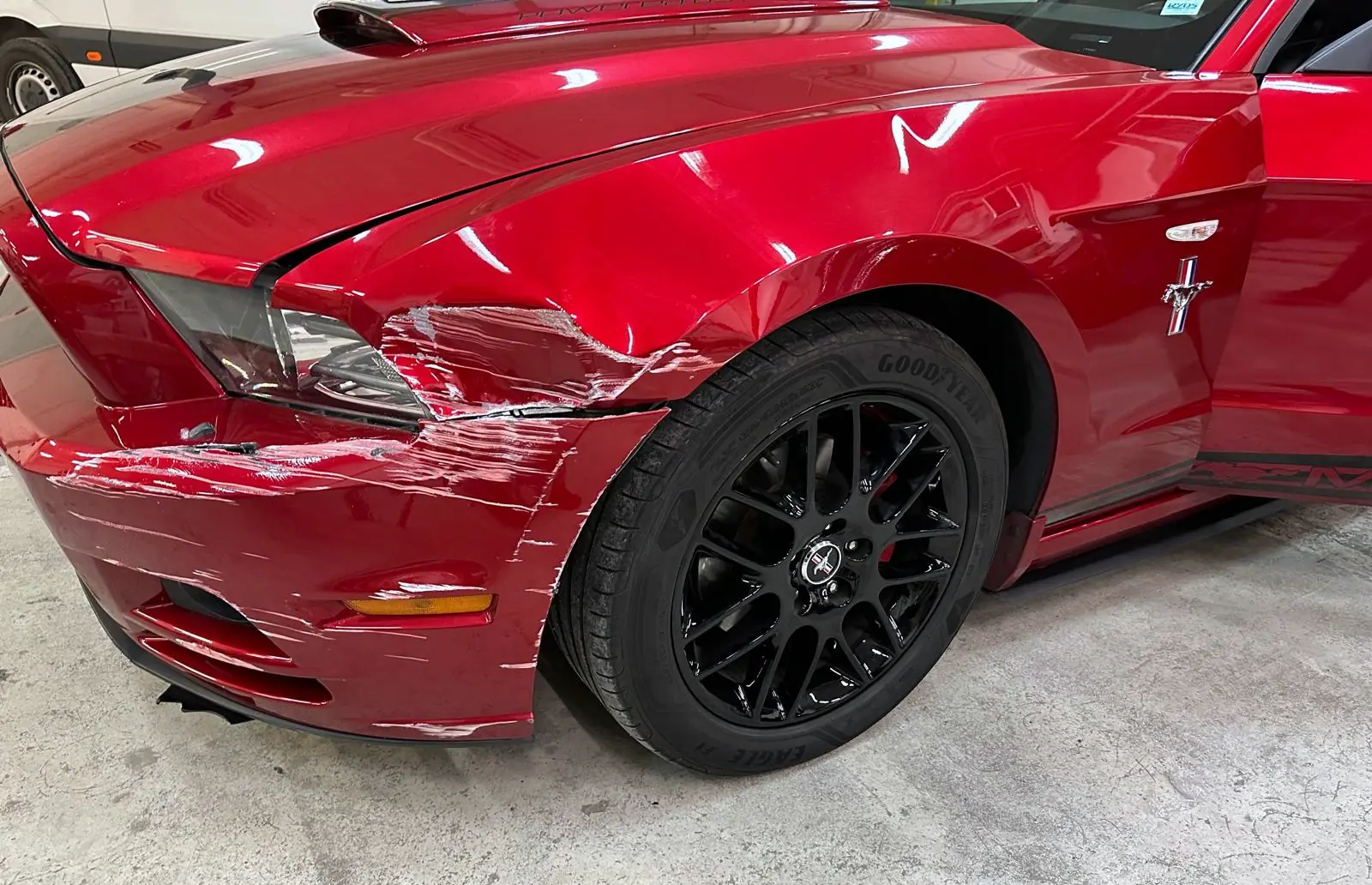 Red Ford Mustang with a damaged bumper and front wing